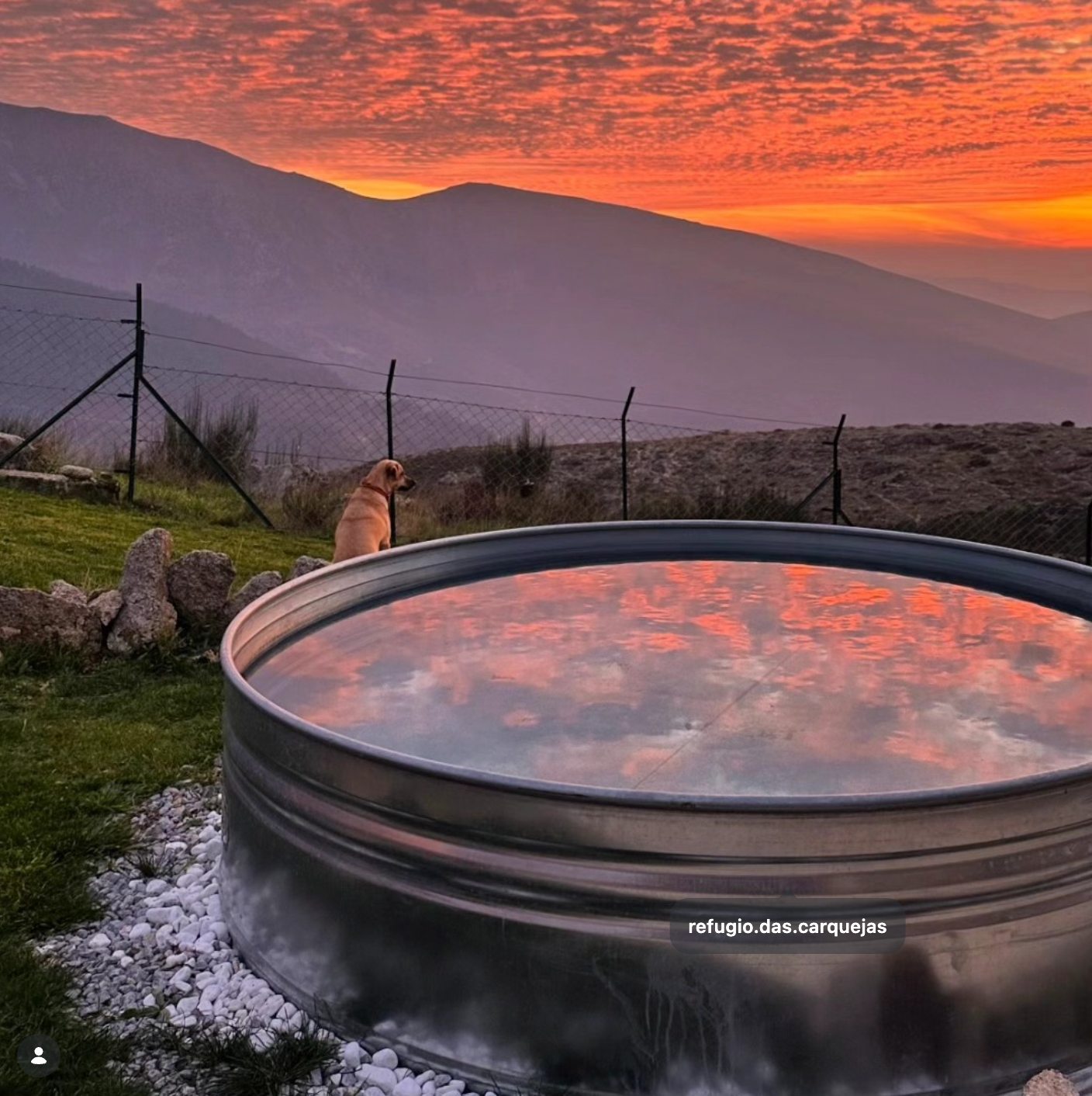A large round galvanized steel stock tank pool on a farm with sunset sky and mountain view in america 
